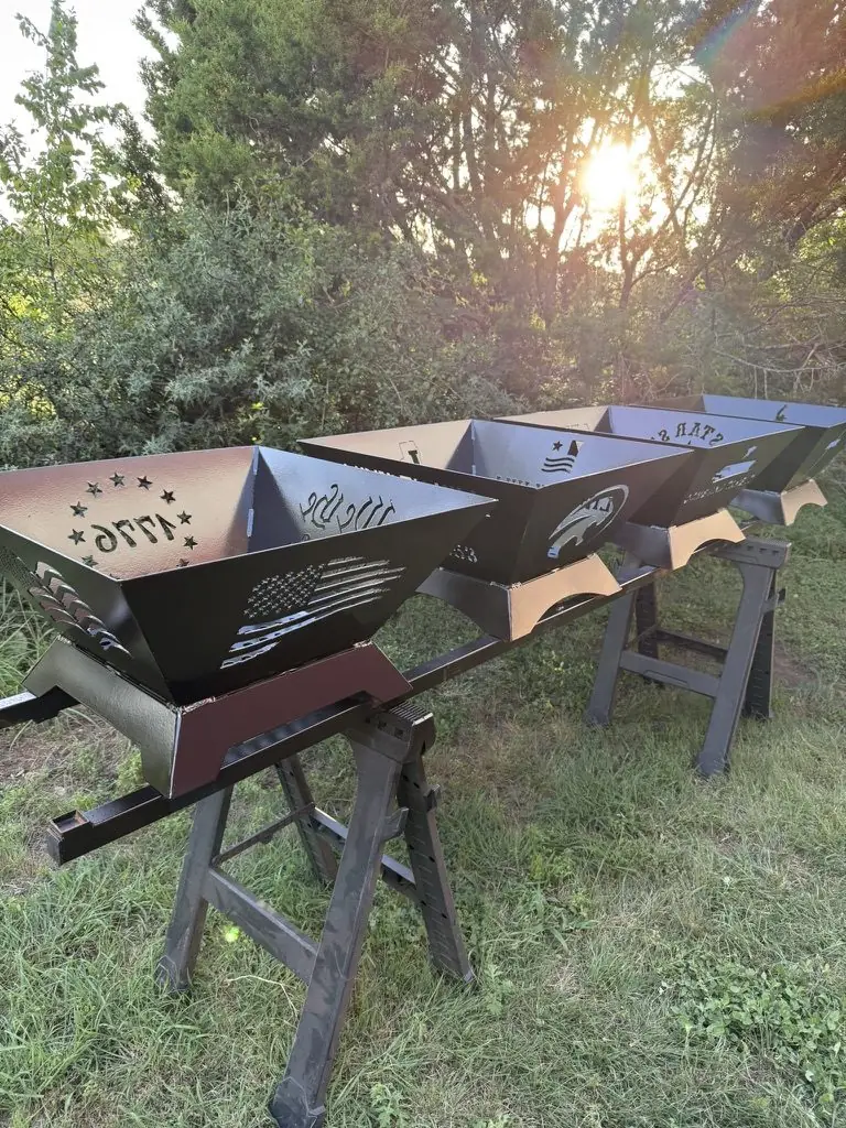 Custom steel fire pits with a cut 1776 flag at sunset