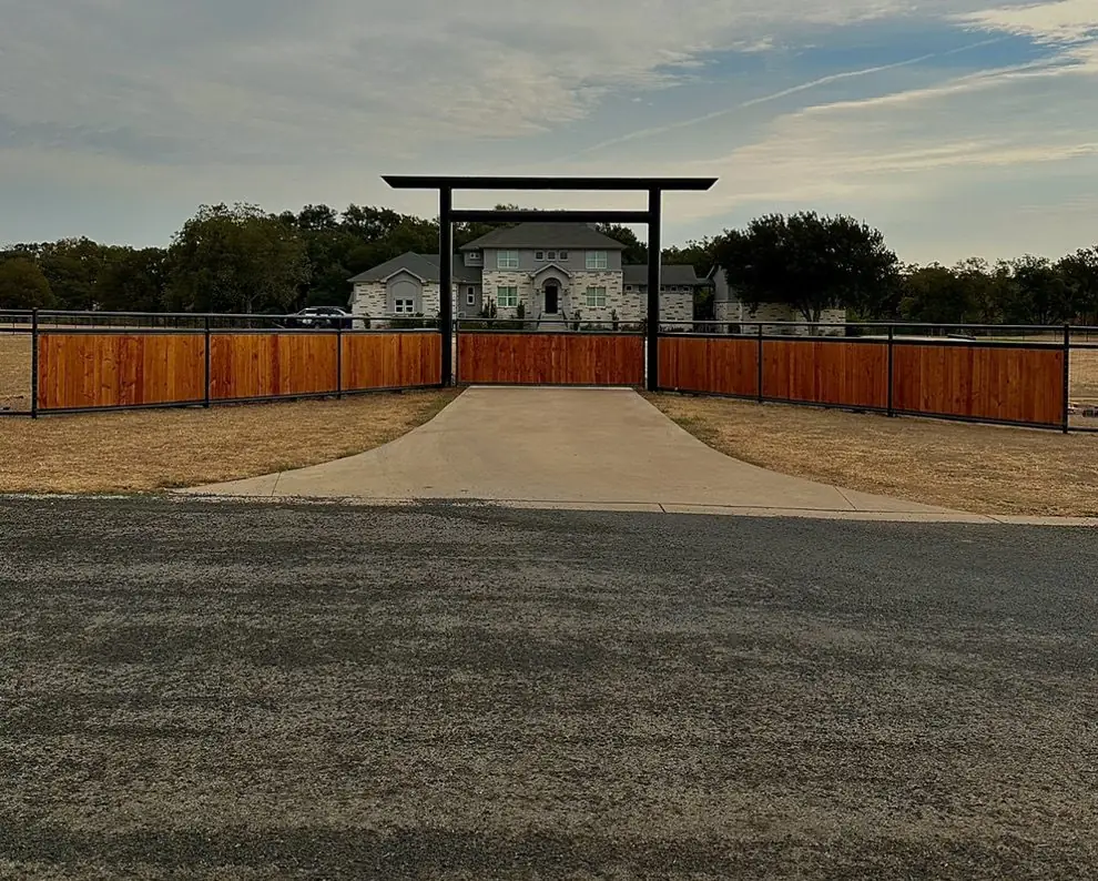 Steel entrance frame over a driveway with wood panel fence