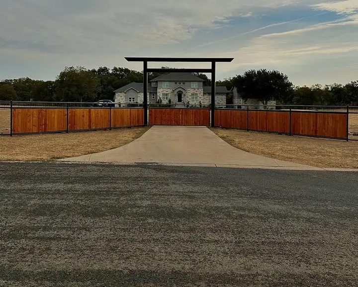 Steel entrance frame over a driveway with wood panel fence