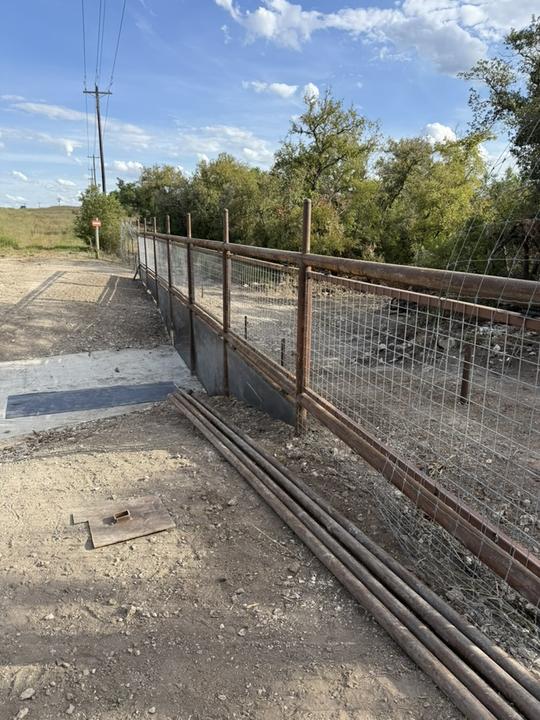 Pipe and wire fence mid-build with pipe stock