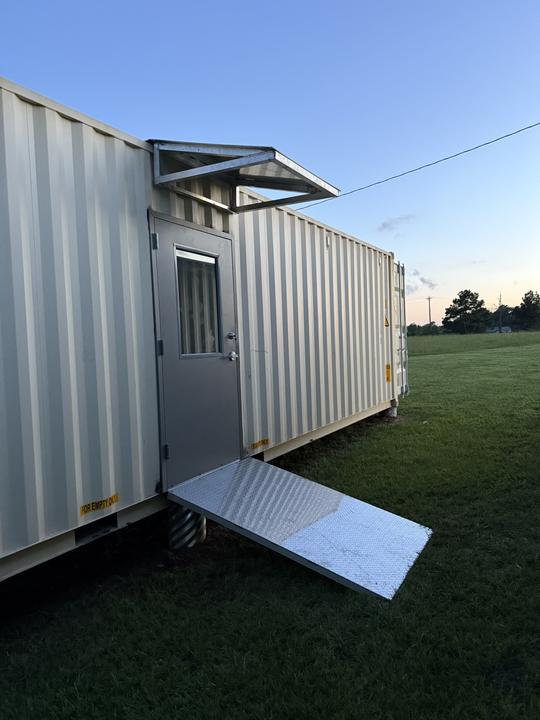 Shipping container door with awning and ramp