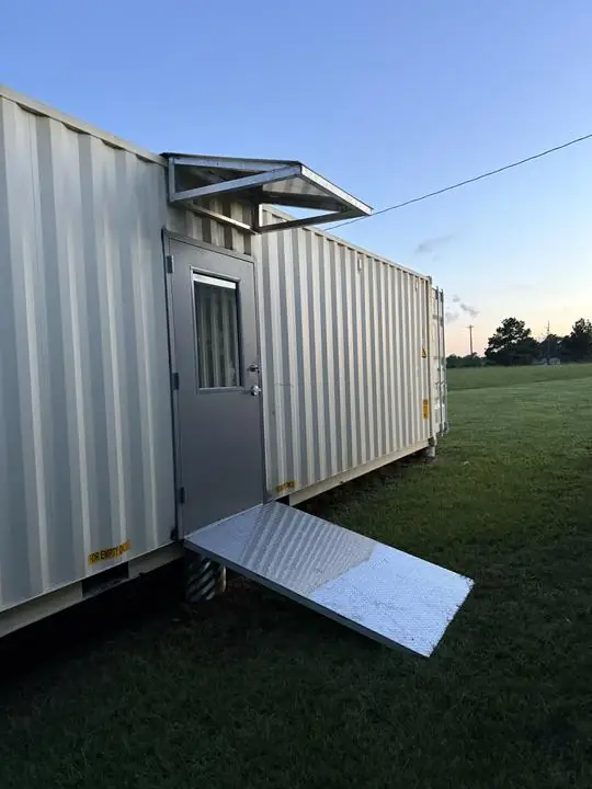 Shipping container door with awning and ramp