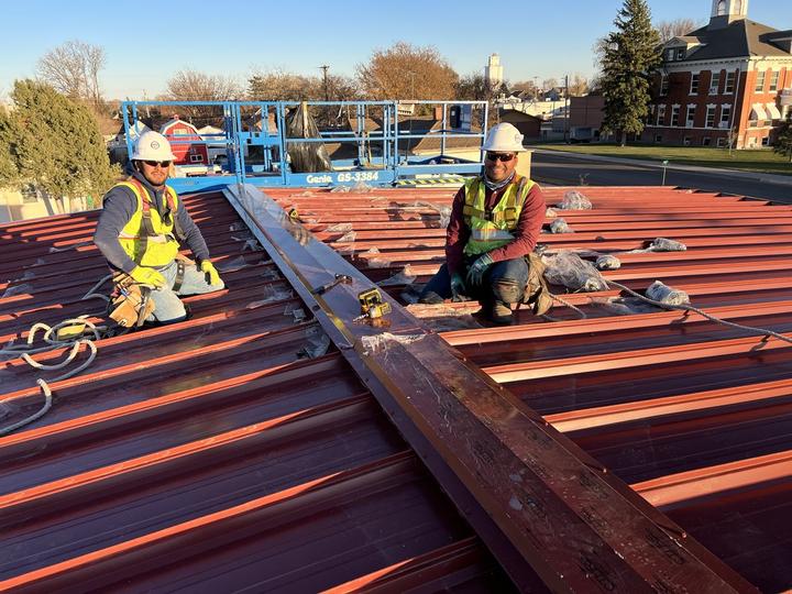 Crew setting ridge cap on a standing seam roof