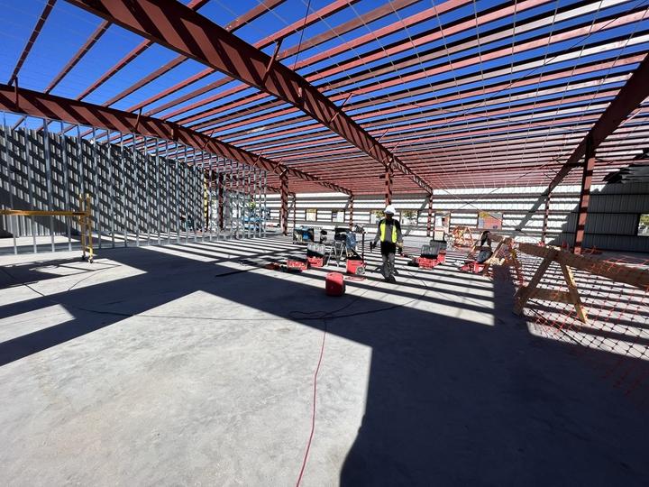 Crew working under a completed red-iron roof frame