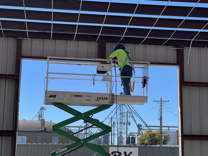 Welder on a lift at an overhead door opening