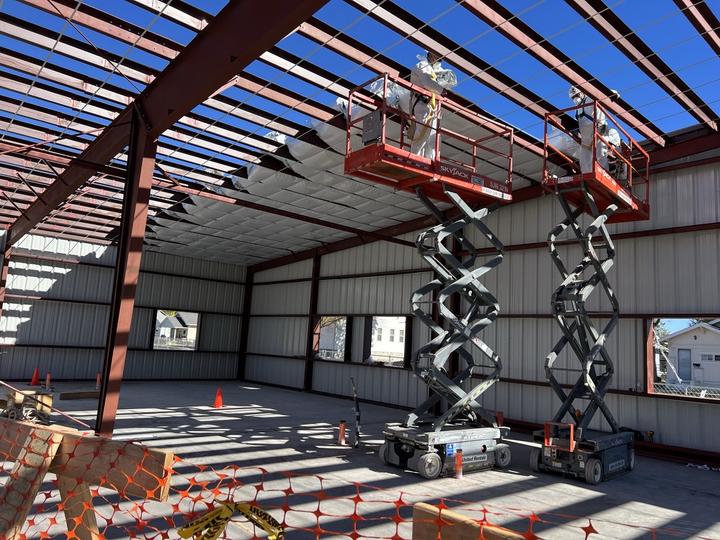 Crew on lifts installing roof insulation over red iron