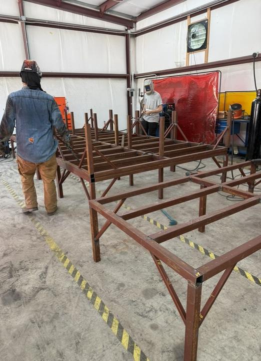Crew welding a row of steel frames in the shop