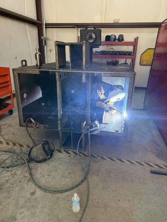 Welding inside a large steel box frame in the shop