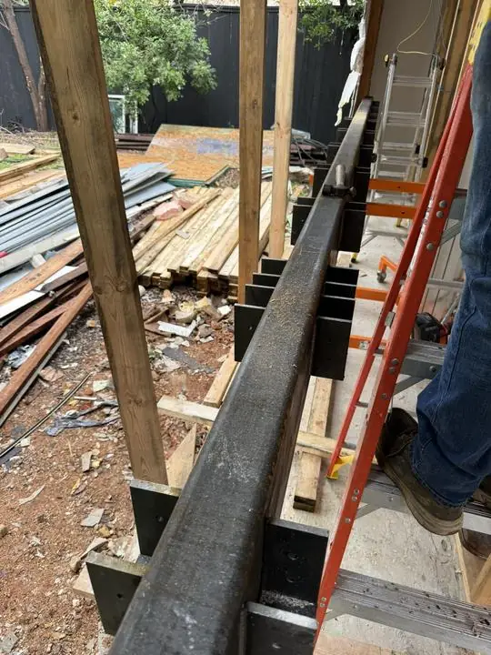 Steel beam with welded plates set in wall framing