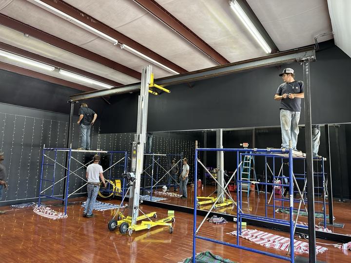 Crew setting overhead steel beam with material lifts