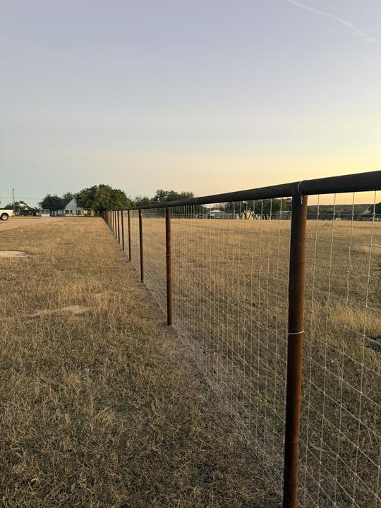 Pipe post and wire ranch fence at sunset