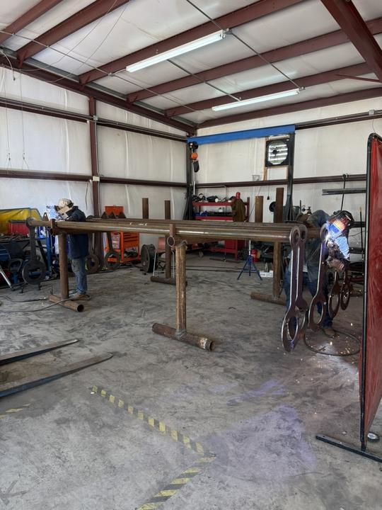 Two welders fitting pipe frames on stands